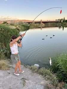 teen girl catching catfish riverfront pond 6 29 24
